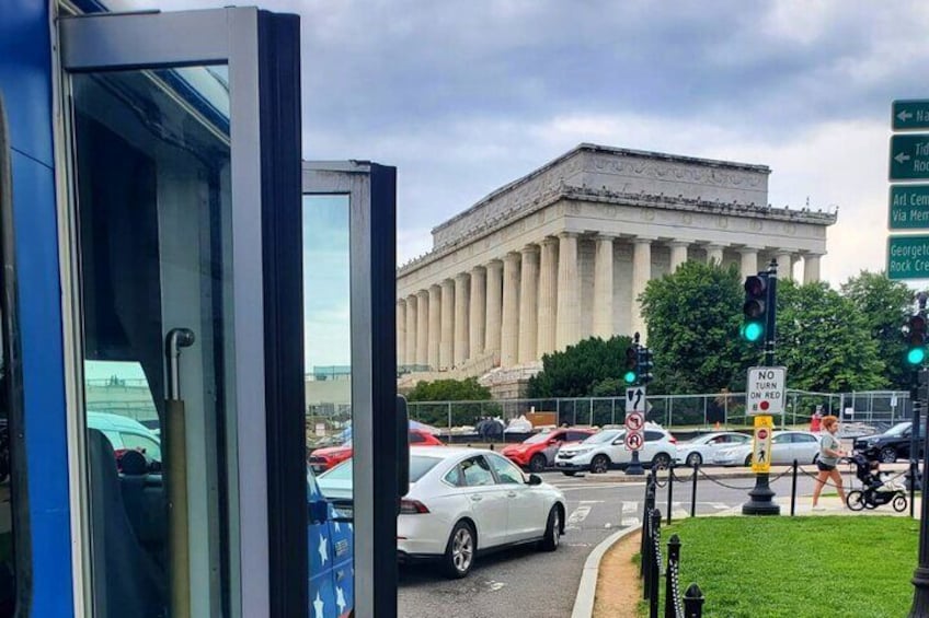A traffic light, a white car, and the Lincoln Memorial in the background. 2