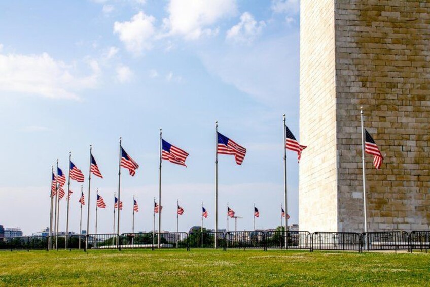 A row of American flags on flagpoles in front of a large brick building. 2