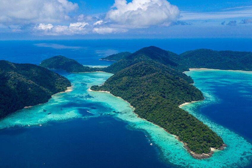 A tropical island landscape with clear turquoise waters, lush green hills, and a small beach. 1