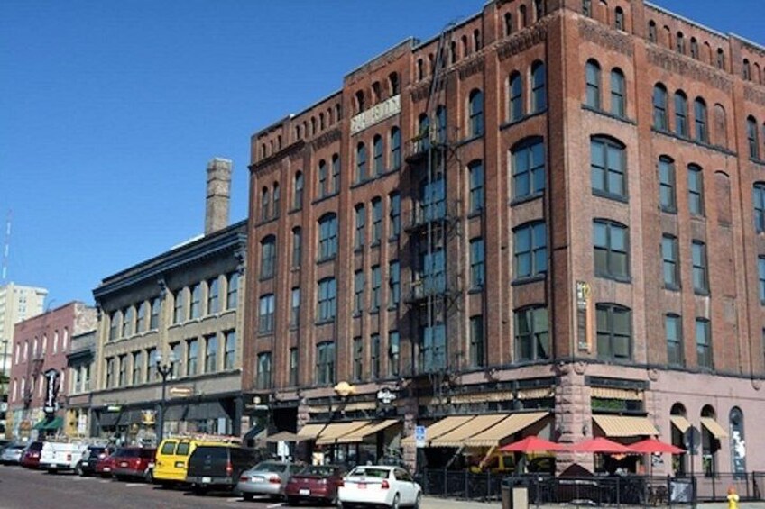 A red brick building with multiple stories, large windows, and a corner location. 4