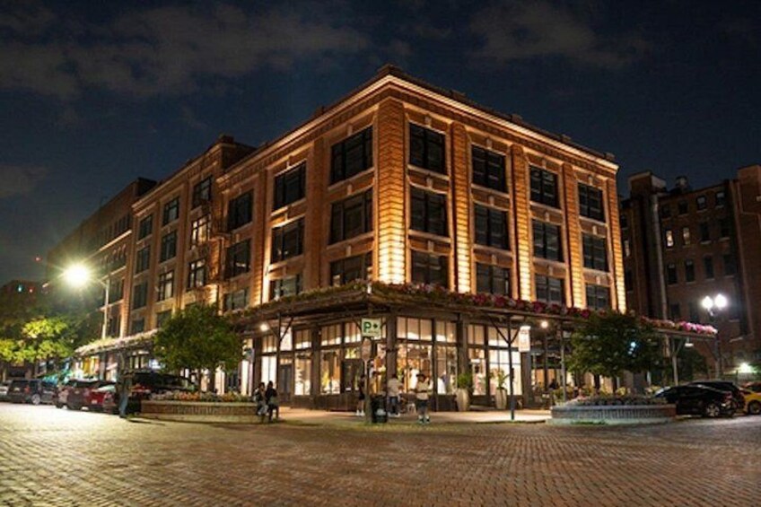 A well-lit, multi-story building with a ground-level entrance and a parking sign. 2