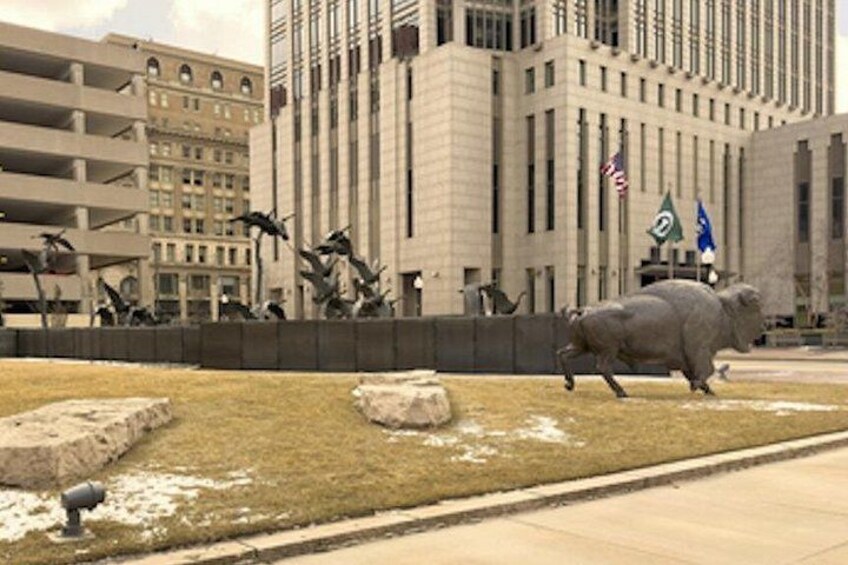 A large building with multiple floors, a grassy area with rocks, and a pig statue. 5