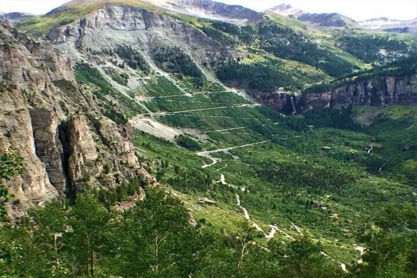 A mountainous landscape with a prominent rock formation and a valley with dense greenery. 4
