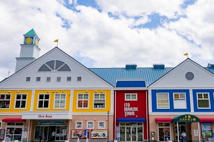 Una hilera de edificios coloridos con letreros que indican Ocean Bazaar, Marine Town y otras tiendas. 4