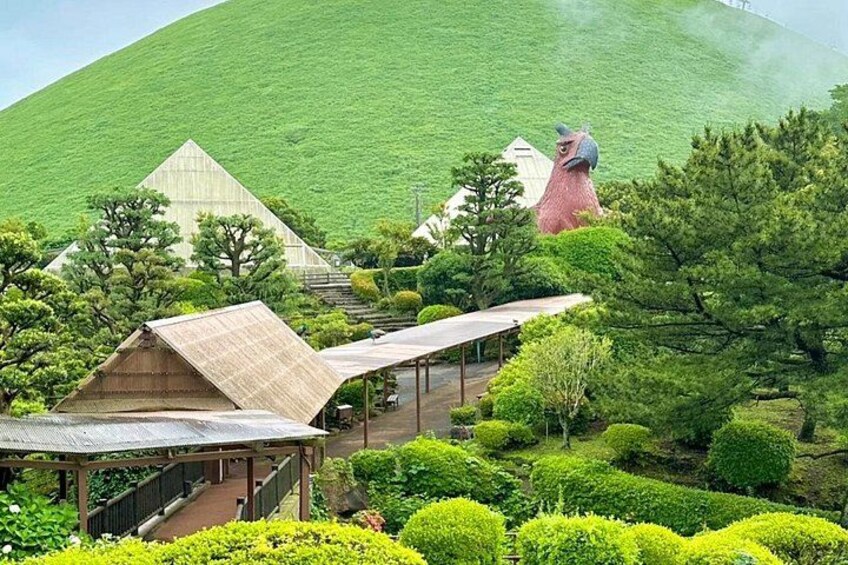 Un jardín japonés tradicional con un edificio de forma piramidal, una estatua roja y setos cuidadosamente recortados. 5