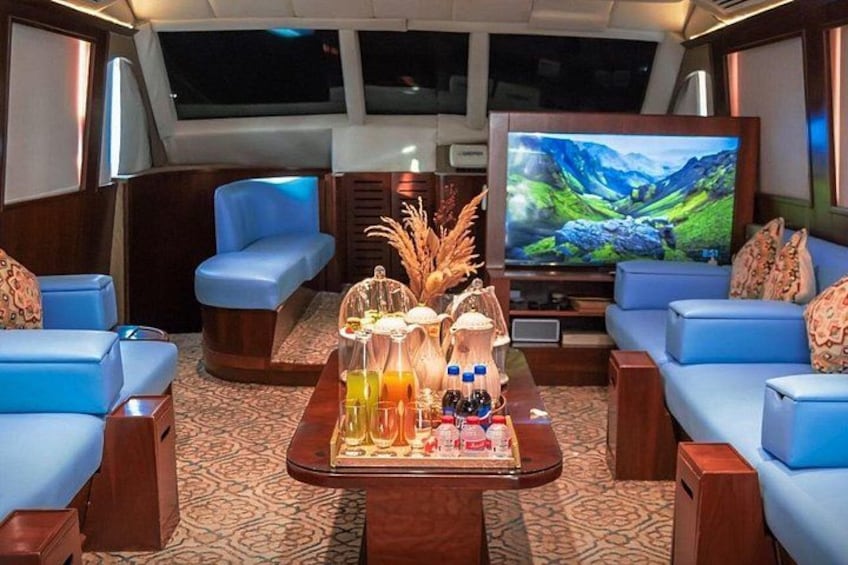 A cozy interior with blue sofas, a wooden coffee table with drinks, and a TV displaying a mountainous landscape. 3