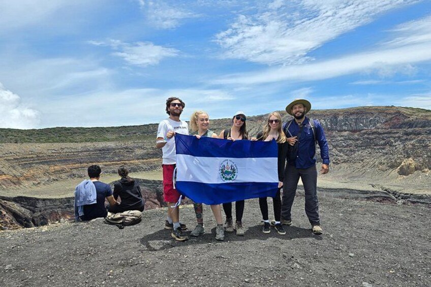 Un groupe de personnes tenant un drapeau, debout sur un terrain rocheux, sous un ciel dégagé. 2