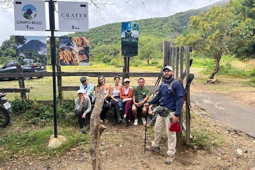 A group of people at a trailhead with signs indicating Campo Bello 1 km and Crater 5 km. 5