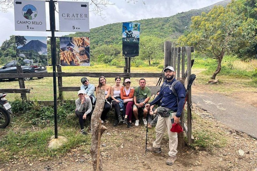 Un groupe de personnes est assis sur un banc près d’un panneau indicateur indiquant les distances vers Campo Bello et Crater. 3