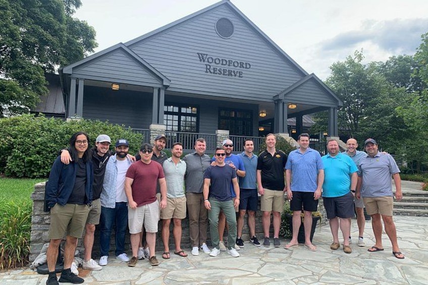 En gruppe mennesker står foran en bygning med skiltet 'Woodford Reserve'. 2