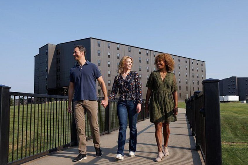 Trois personnes marchent sur un pont, avec un bâtiment en arrière-plan. 5