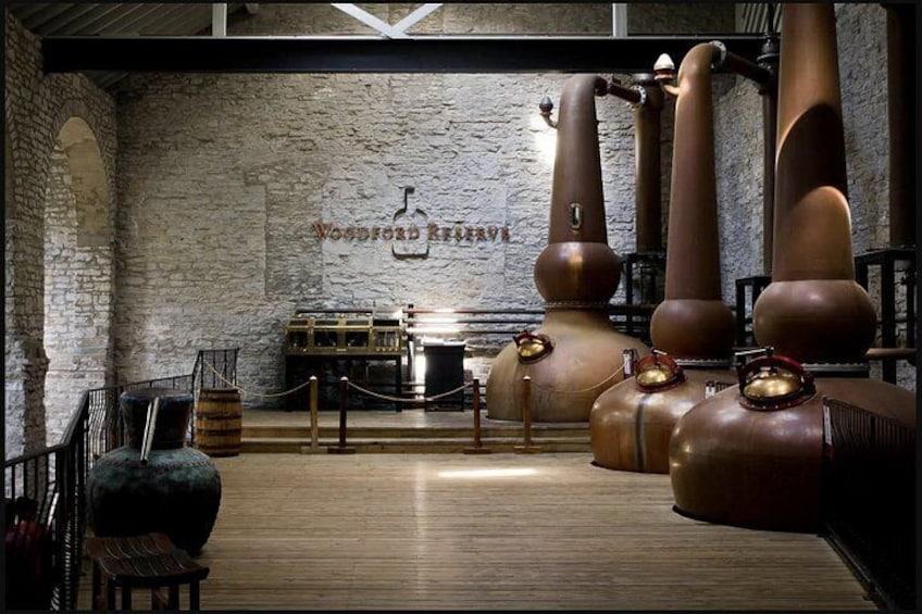 L’intérieur d’une distillerie, avec de grandes cuves de cuivre, des barriques en bois et un mur en pierre. 2