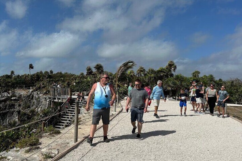 Een groep mensen loopt over een verhard pad langs het strand. 3