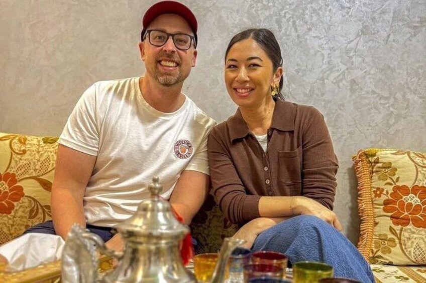 Two people sitting on a couch with a table in front of them. 2