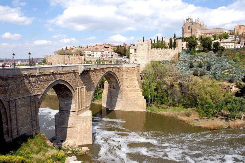 Un puente de piedra sobre un río, con un castillo y edificios al fondo. 2