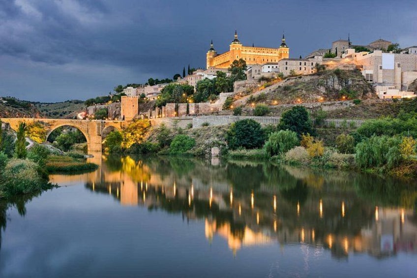 Un paisaje urbano histórico con un castillo destacado, un puente y un río tranquilo que refleja la arquitectura. 5
