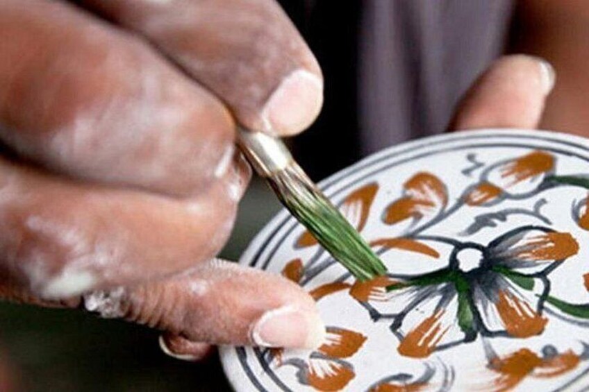 Une personne qui peint un motif floral sur une assiette en céramique. 5