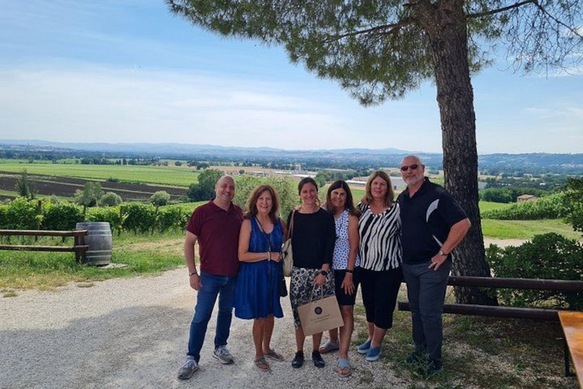 A group of people standing on a gravel path with a scenic view of rolling hills and fields in the background. 2