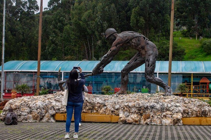 A person taking a photo of a sculpture of a man in a crouched position. 2