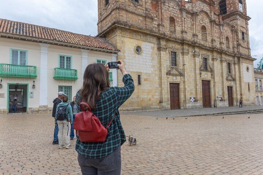 Un edificio histórico con una torre de reloj, calle adoquinada y personas tomando fotos. 5