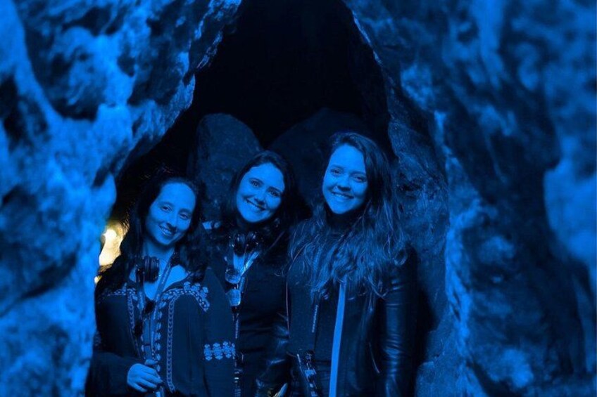 Three people standing in a cave with blue lighting. 1