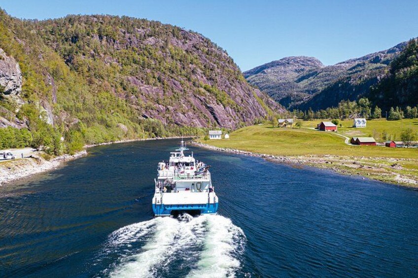 En båt färdas på en flod med hus och berg i bakgrunden. 2