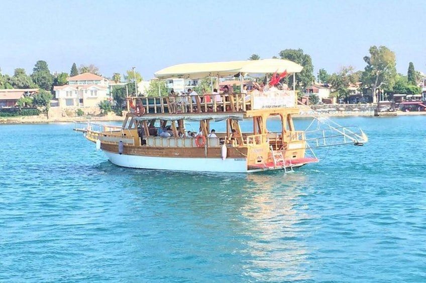 A wooden boat with a canopy, passengers, and a waterfront backdrop. 4