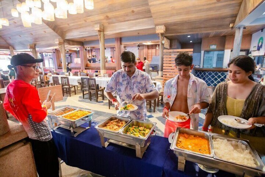 A buffet with various food items and people serving themselves. 2