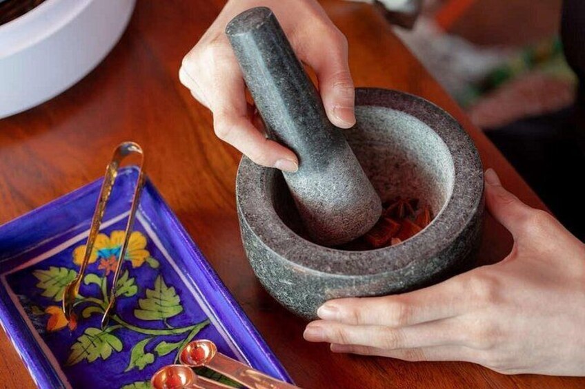 A person using a mortar and pestle on a wooden surface. 5