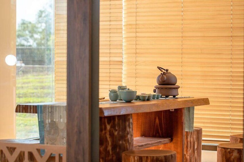 Una mesa de madera con vajillas de té tradicionales y una tetera. 2