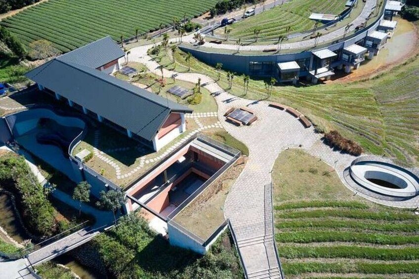 Un edificio moderno con techo curvo, rodeado de jardines ajardinados y una entrada circular. 3