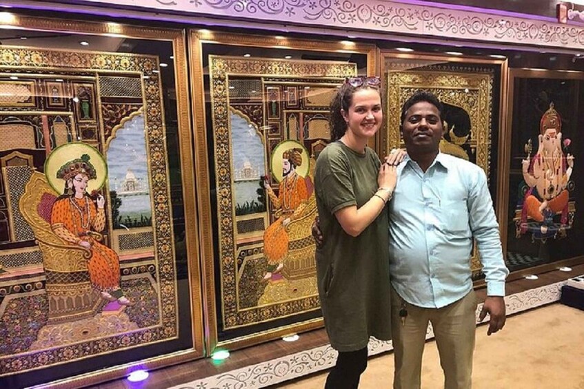 Two people standing in front of ornate framed paintings. 2