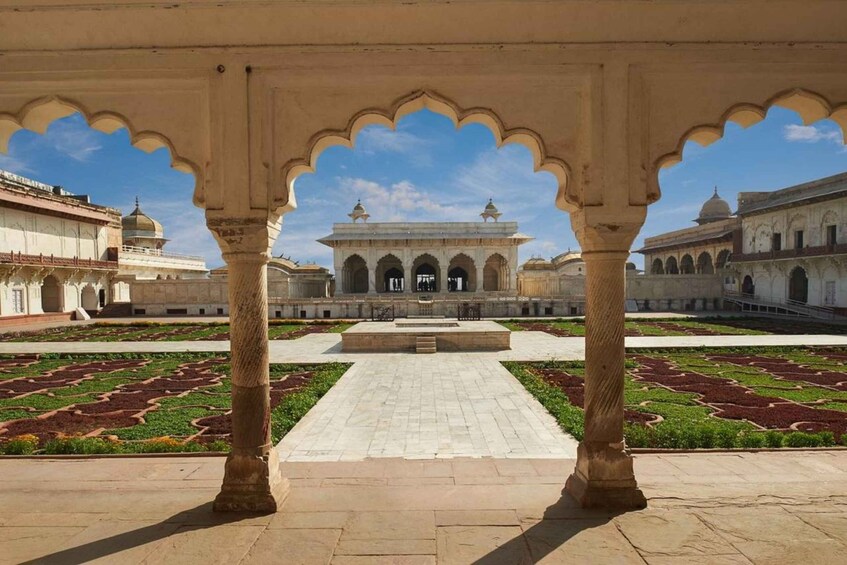 A courtyard with a central building, surrounded by arches and a patterned garden. 4