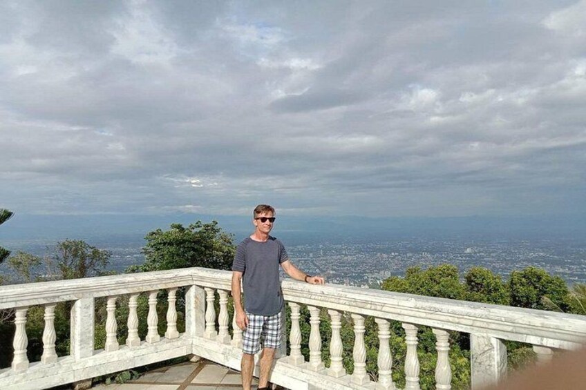 A person standing on a balcony with a cityscape in the background. 3
