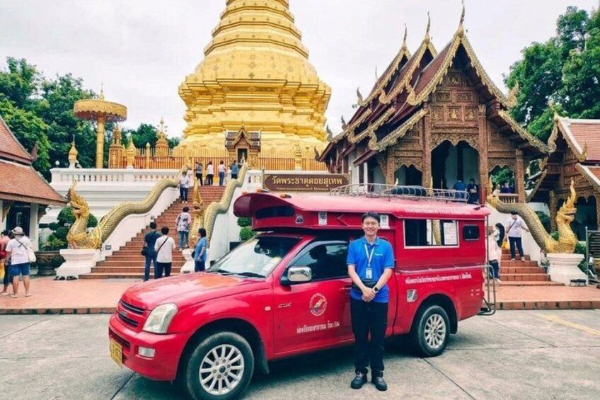 Un tuk-tuk rosso parcheggiato di fronte a uno stupa dorato e un edificio tradizionale. 1