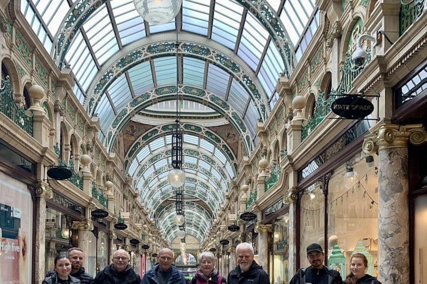 A historic indoor market with a glass ceiling, ornate columns, and a group of people standing in the center. 4