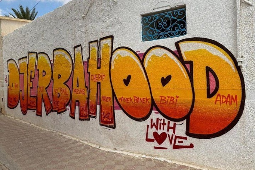 A wall with graffiti art spelling 'JERBAHOOOD' with names and a heart symbol. 3