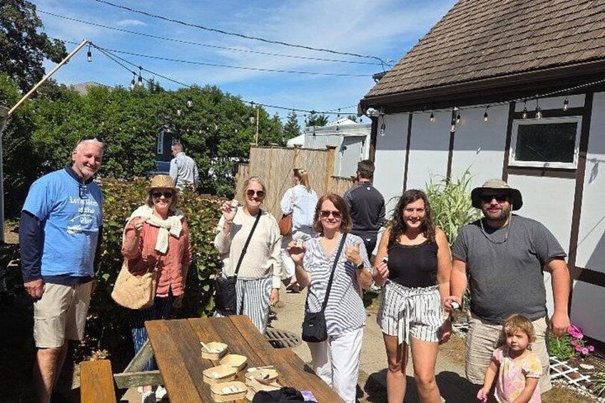 A group of people standing in a backyard with a wooden table and chairs. 3