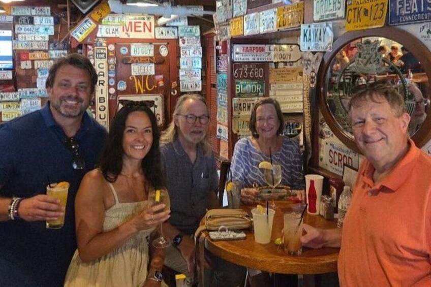 A group of people at a bar with various signs and memorabilia on the walls. 5