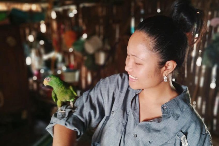A person holding a green parrot. 3