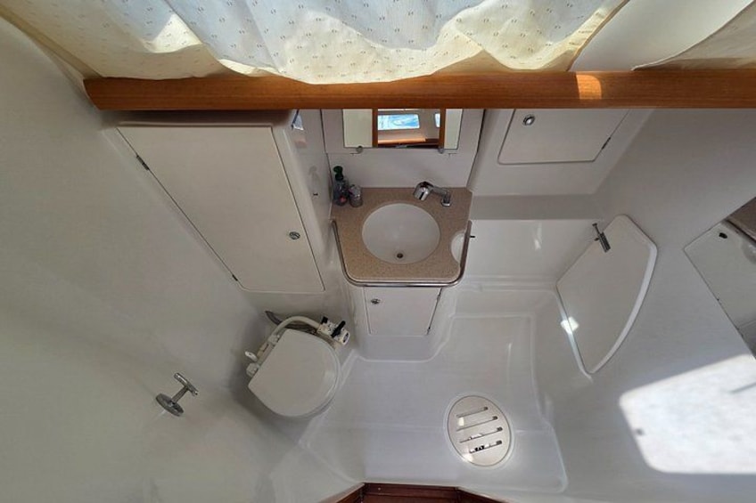 Une petite salle de bain comprenant des toilettes, un lavabo et une douche. 2