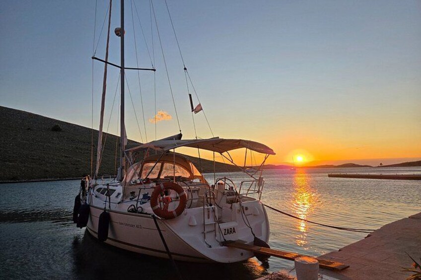 Ein Segelboot liegt im Abendlicht in einer Marina vor Anker. 2