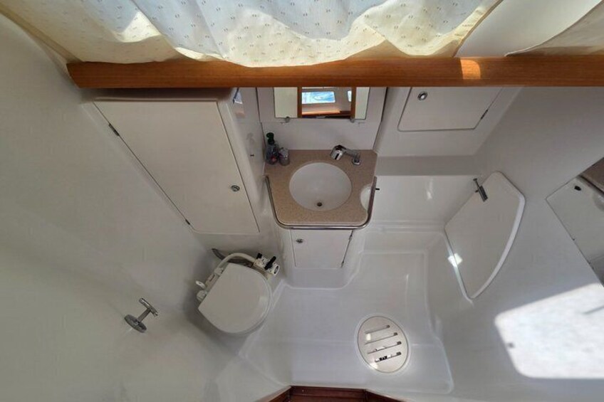 A compact bathroom with a toilet, sink, and shower area. 2