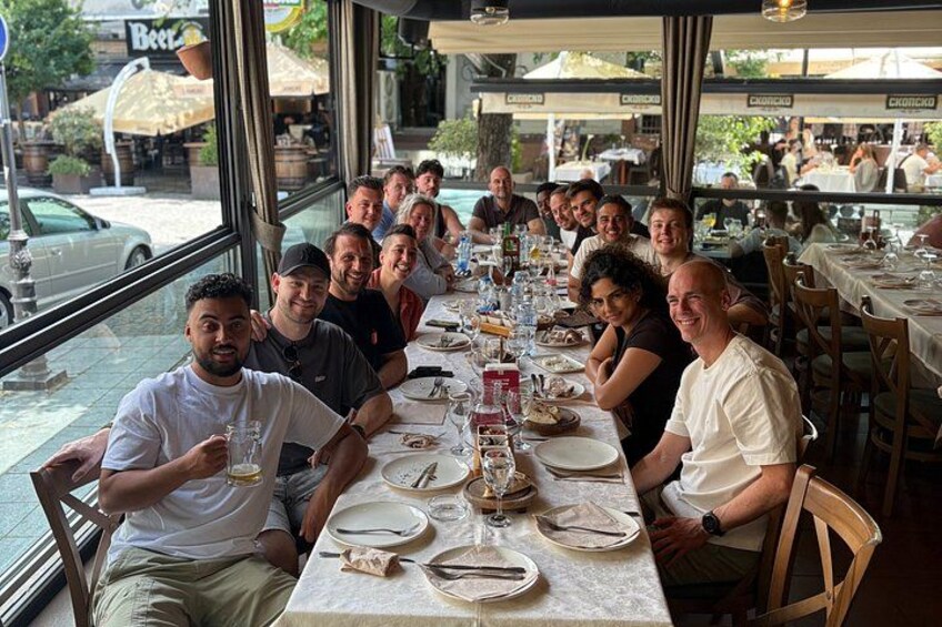 Een groep mensen eet in een restaurant met terras, met grote ramen met uitzicht op een straat. 4