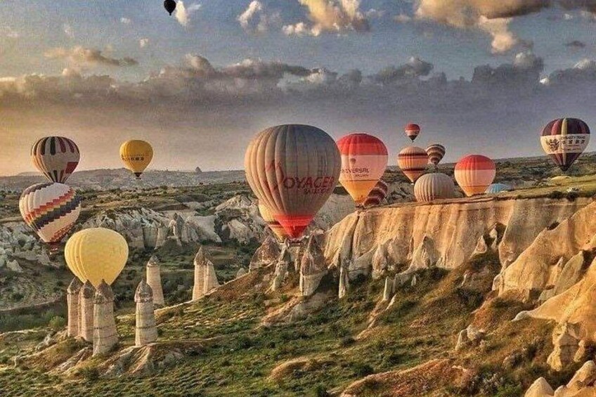 A landscape with hot air balloons, rocky terrain, and a clear sky. 4