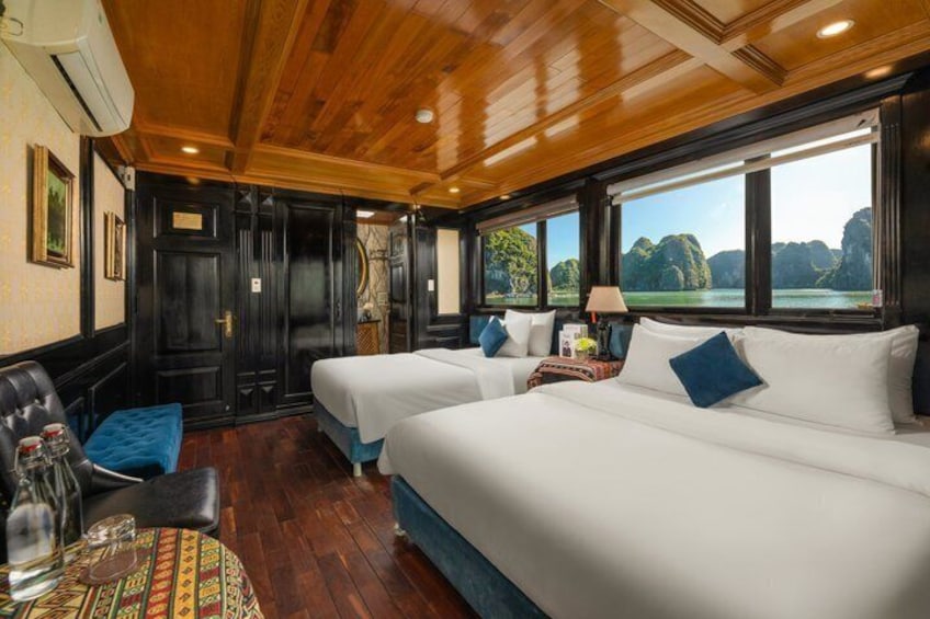 A cabin with two beds, wooden ceiling, and a view of the sea. 4