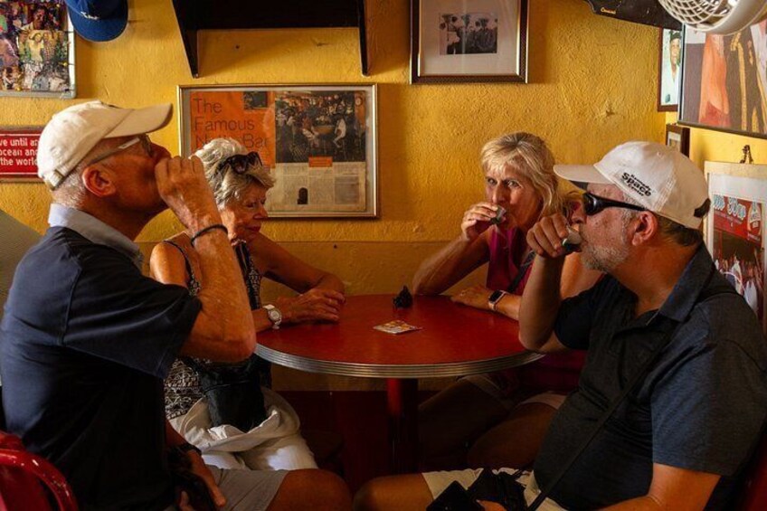 A group of people sitting around a red table in a restaurant with yellow walls and framed pictures on the wall. 3