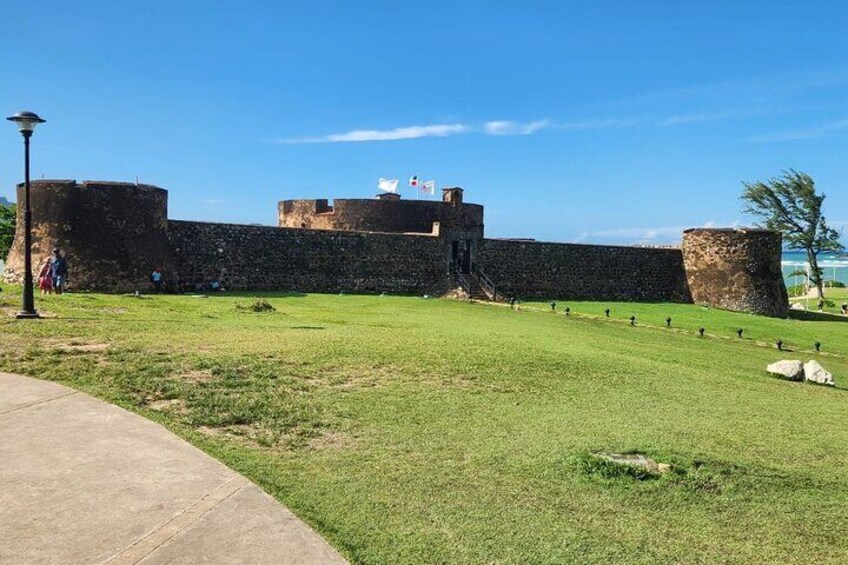 A historic stone fort with a grassy foreground and a clear blue sky. 1