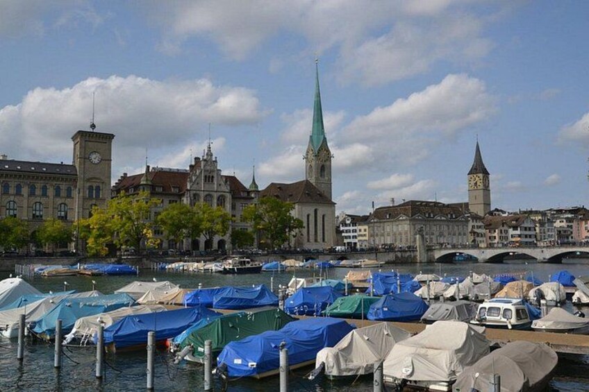 A harbor with boats, a clock tower, and a church with a green spire. 4