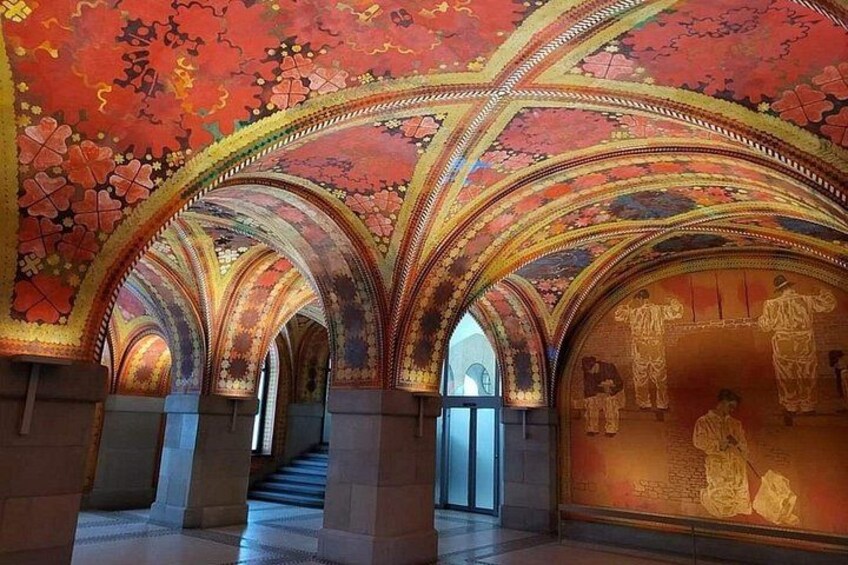 An interior with arched ceilings and detailed wall murals. 2